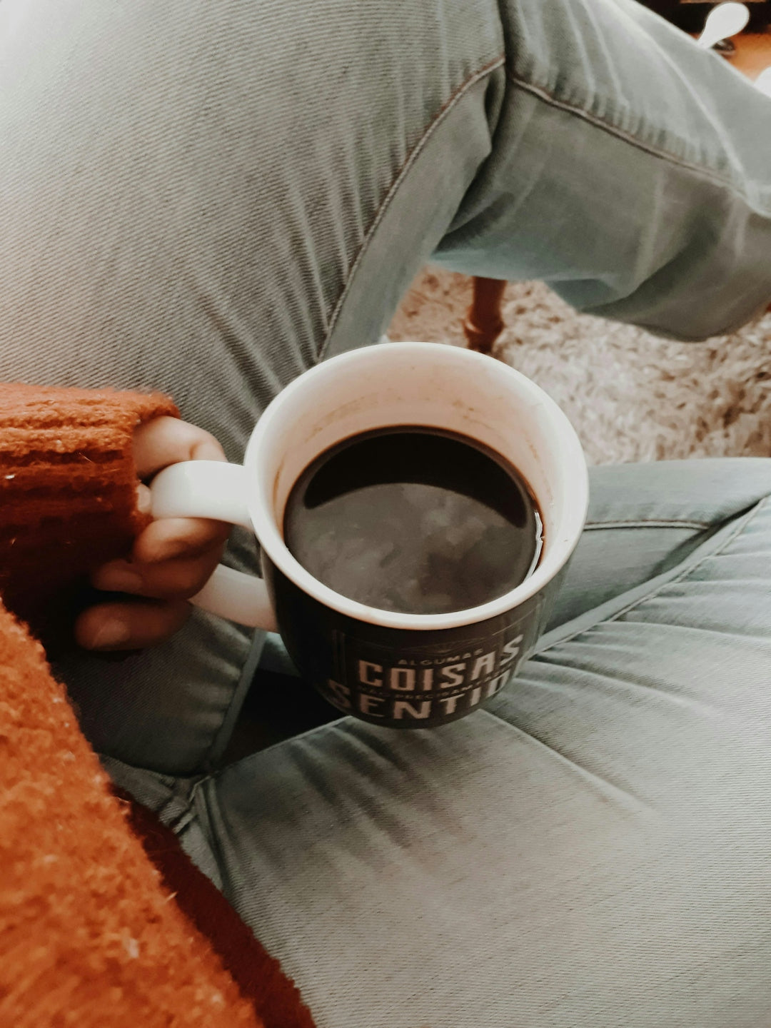 a person sitting on a couch holding a cup of coffee
