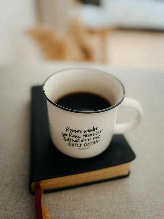 A mug of coffee rests on a closed book.