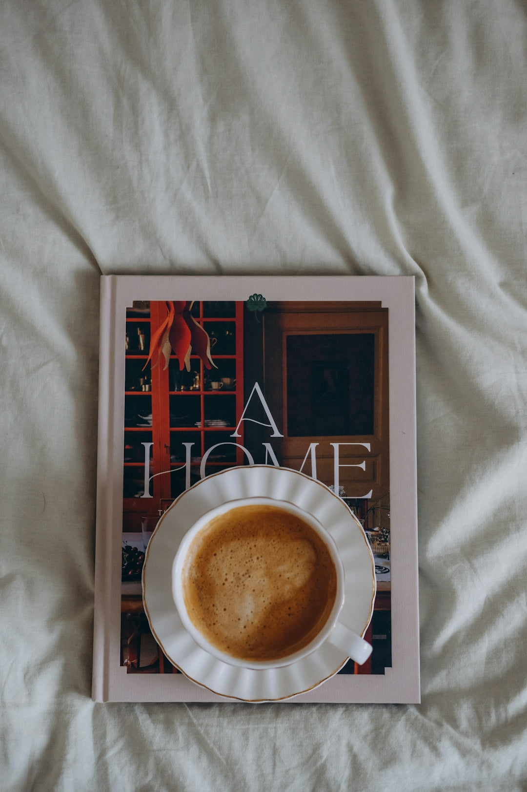Cup of coffee on a book on a bed