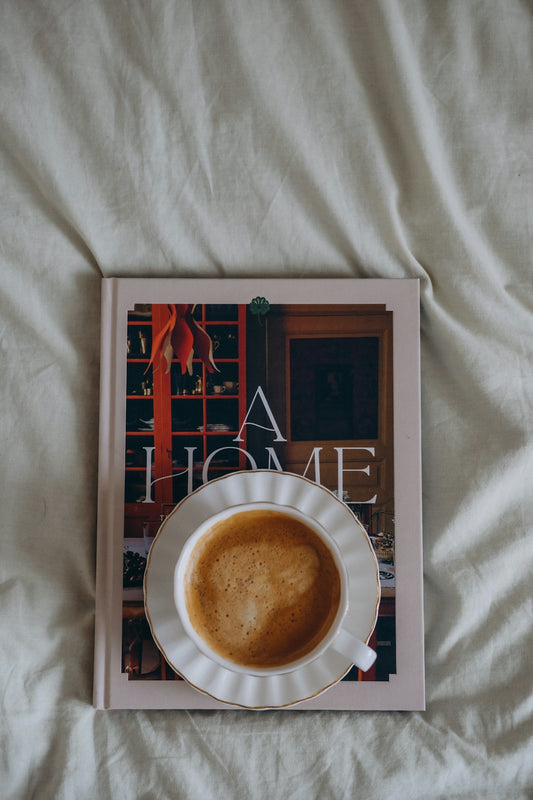 Cup of coffee on a book on a bed
