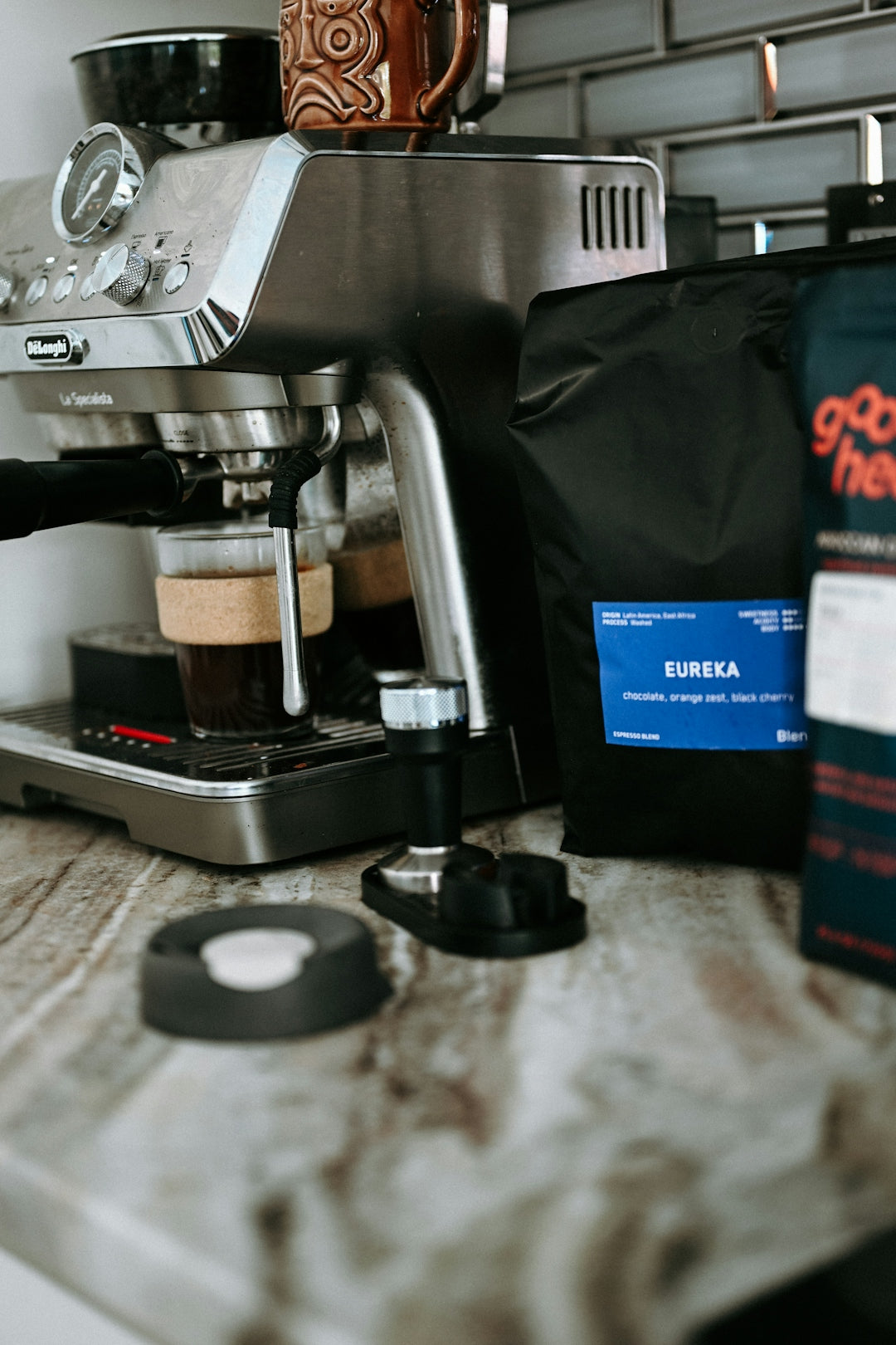 Espresso machine brewing coffee next to coffee beans.